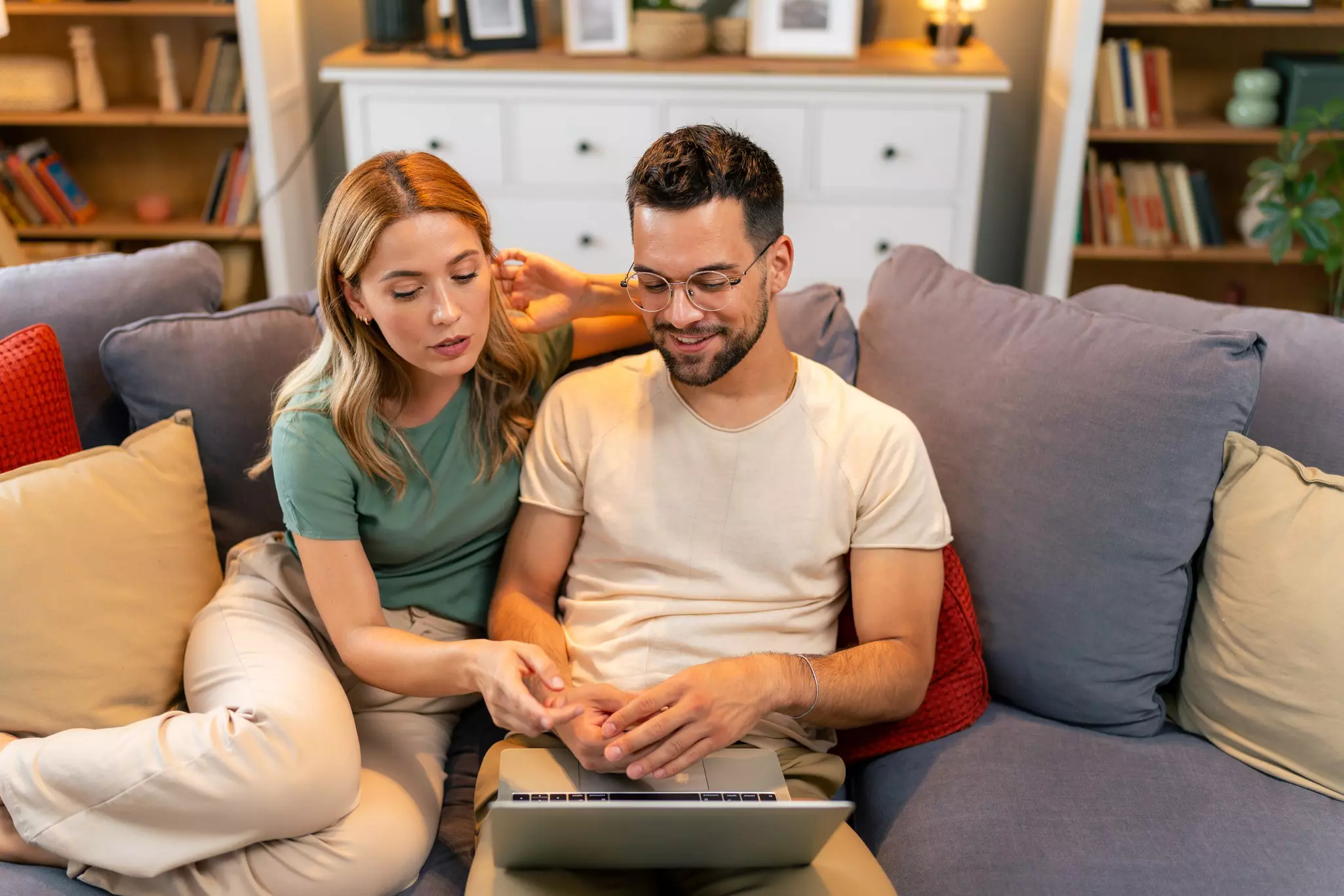 Junges Paar mit Laptop auf einem Sofa in ihrem Wohnzimmer