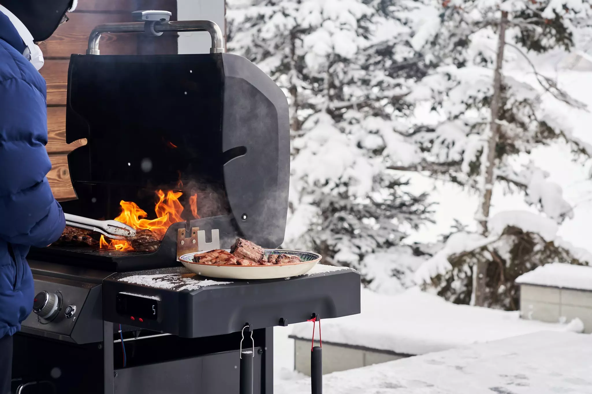 Anwendung Flaschengas - Person grillt an Gasgrill im Schnee auf einer Terrasse